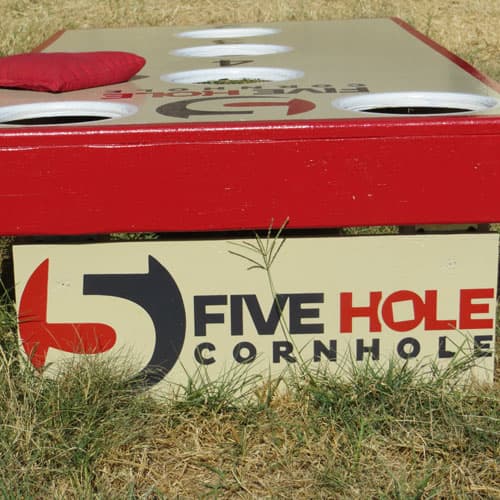 Red-trimmed 5-Hole cornhole board with the Five Hole Cornhole logo on its back panel