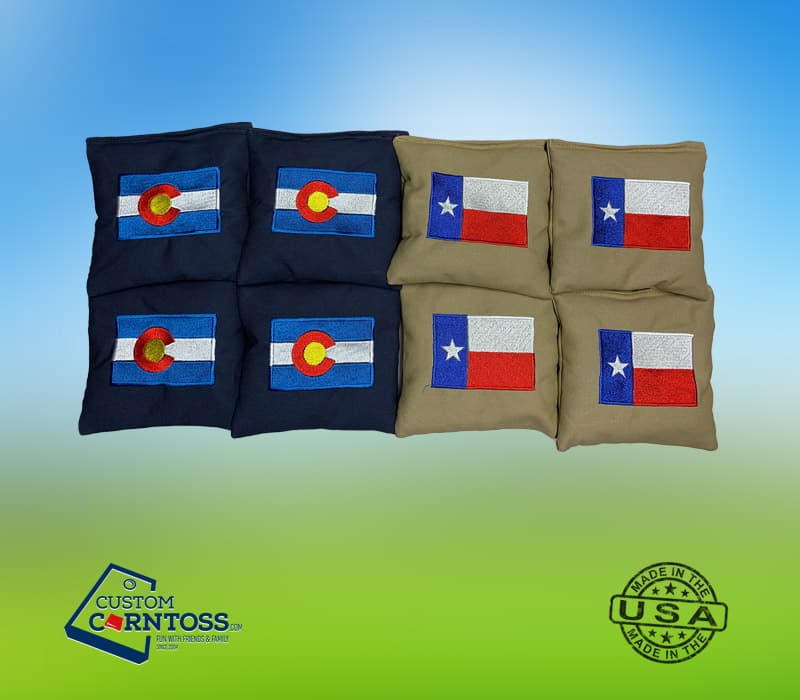 Eight embroidered cornhole bags, four navy with Colorado flags and four tan with Texas flags