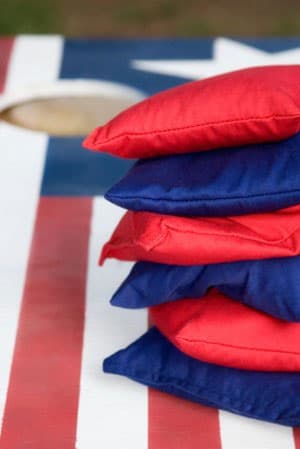 Stack of red and blue cornhole bags resting on an American flag cornhole board