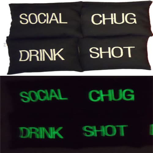 Black cornhole bags embroidered with drinking game words that glow green in the dark