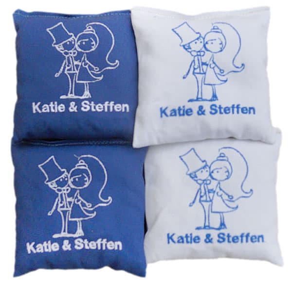 Blue and white wedding cornhole bags embroidered with a bride and groom drawing and names