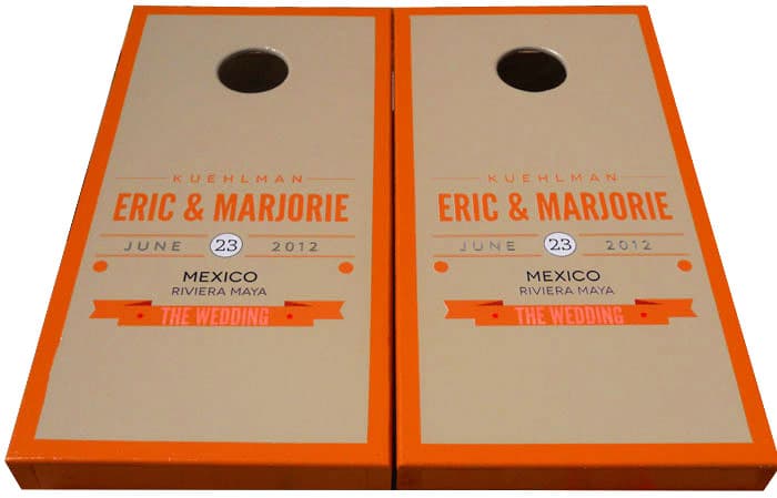 Custom wedding cornhole boards with orange trim, the couple’s names, and the wedding date